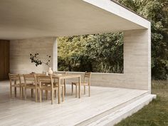 a dining table and chairs on a wooden deck in front of a large open area