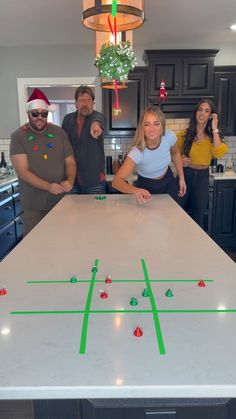 three people are standing around a table with a game on it and one person is pointing at the camera