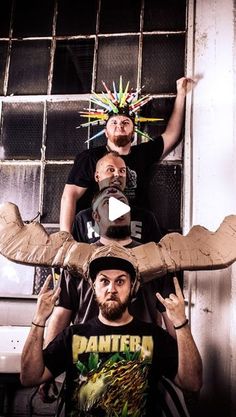 three men standing in front of a window with an eagle on their head and one man wearing a t - shirt that says danger