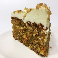 a piece of carrot cake with white frosting and walnuts on top is sitting on a plate