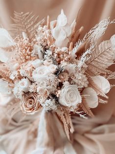 a bridal bouquet with white and pink flowers on a beige cloth draped in the background