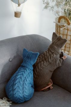 two knitted animals are sitting on a gray couch in front of a hot air balloon