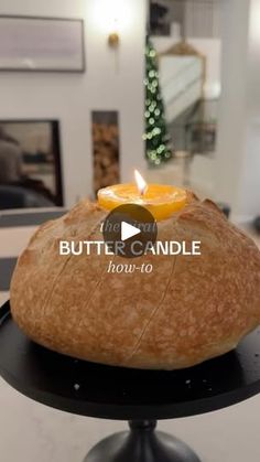 a loaf of bread sitting on top of a black cake plate with a lit candle in it