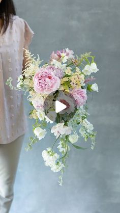 a woman holding a bouquet of pink and white flowers