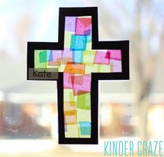 a cross made out of colored paper on a window sill with the word kate written below it