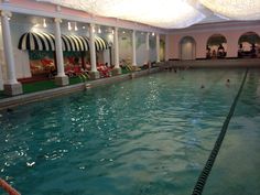 an indoor swimming pool with people in the water and chairs around it, all lined up