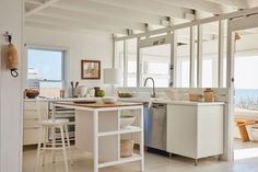 a kitchen with white cabinets and an island in front of the sink is open to the dining room