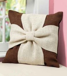 a brown and white pillow with a bow on it sitting next to a window sill