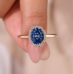 a woman's hand holding a blue diamond ring