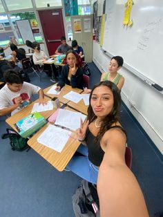 a group of young people sitting at desks in a room with writing on them