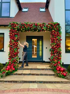 a woman standing in front of a house decorated with christmas garland and poinsettis