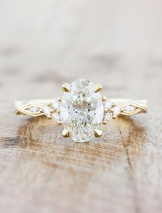 an oval cut diamond ring with three smaller diamonds on the band, set in yellow gold