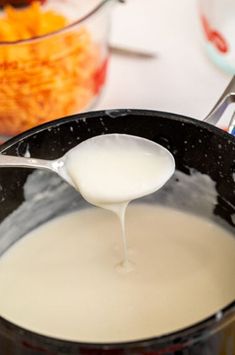 a spoon is pouring milk into a pot