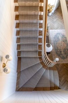 an overhead view of a staircase with carpeted steps and wood handrails in a home