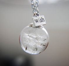 a dandelion with the word wish written on it is hanging from a chain