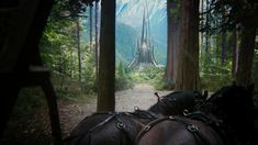 two horses are pulling a carriage down a path in the woods with a castle in the background