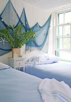 two beds in a room with blue bedding and green plants on the headboard