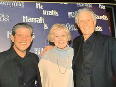 three people standing next to each other in front of a blue wall with the words harrah's written on it