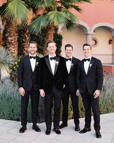 four men in tuxedos are posing for a photo outside the building with palm trees