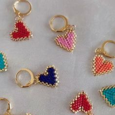 six pairs of beaded heart shaped rings on a white cloth with gold clasps