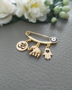 Hindu Elephant Pin, Gold Hindu Pin, Hindu Symbols Om Elephant Hamsa Charms Pin, Hindu Jewelry, Hindu Gift for Child or Adult This is a beautiful Hindu pin featuring 18k gold plated Ohm round pendant, hamsa and elephant charm size 4cm long, great size to pin on a baby blanket or clothes. This makes a beautiful and unique gift for a new baby which will be treasured forever. A perfect gift for either a new mum on the birth of her baby, or a gift for Mother's Day or a baby shower. Thanks for visitin Hindu Jewelry, Hindu Elephant, Hindu Symbols, Italian Gifts, Horn Pendant Necklace, Godparent Gifts, Hamsa Charm, Lucky Elephant, Protection Amulet