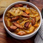 a bowl filled with meat and vegetables next to bread