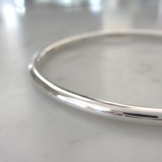 "This handmade heirloom quality sterling silver bangle is such a classic! Made from 3.2mm wide solid round sterling silver, it has such a pleasing weight. It is hand-formed and forged by me... the silver then gets hammered, hammered and hammered some more, creating a surface fully covered in tiny facets that provide a perfectly understated sparkle. The silver has been lovingly sanded and given a polished finish. Available in smooth (unhammered) finish as well, as can be seen in the last two pics Nickel Free Sterling Silver Classic Bangle, Silver Oval Bangle With Polished Finish, Classic Sterling Silver Nickel-free Bracelet, Handmade Classic Round Sterling Silver Bracelet, Nickel-free Classic Sterling Silver Bracelet, Minimalist Sterling Silver Bangle With Shiny Finish, Gift Bangle With Sterling Silver Clasp, Classic Nickel-free Round Bangle, Hoop Bracelet With Polished Finish As A Gift