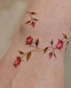 a woman's foot with red flowers on it and leaves all over the ankle