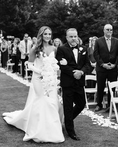 a bride and groom walking down the aisle at their outdoor wedding ceremony in black and white