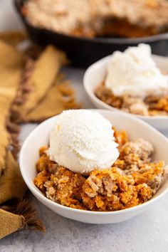 two bowls filled with dessert and ice cream on top of a white tablecloth next to other dishes