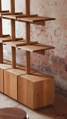 a wooden shelf sitting on top of a hard wood floor next to a brick wall