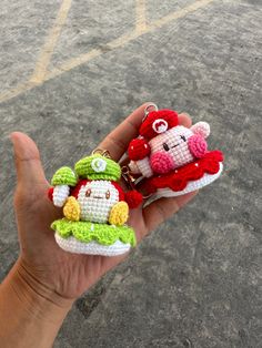 a hand holding two small crocheted items in it's palm, one with a monkey on top