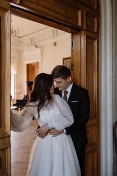 a man and woman standing next to each other in front of a door with their arms around each other