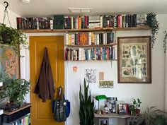 a bookshelf filled with lots of books next to a yellow door in a room