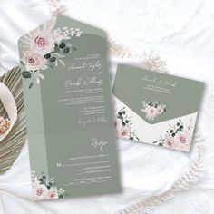 the wedding stationery is laid out on top of a bed with flowers and greenery