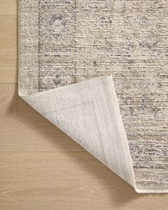 an area rug on the floor next to a piece of wood with a gray and beige color scheme