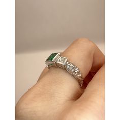 This 18k diamond and emerald ring is perfect for everyday wear.It weighs 6.88 grams and is a size 6.75. The center emerald weighs 0.70 carats and is accompanied by two side diamonds weighing a total of 0.28 carats, providing a subtle yet elegant touch to any outfit.  Condition: In very good condition with some minor surface wear consistent with age. Ring size: 6.75 Markings: “750" "T864" "18k" Metal: 18k White Gold Weight: 6.88 grams Diamonds: 0.28 carats Emerald: 0.70 carats Heirloom Emerald-cut Ring With Single Cut Diamonds, Heirloom Emerald Cut Ring With Single Cut Diamonds, Green Emerald Ring With Diamond Accents In Platinum, Platinum Emerald Ring With Diamond Accents, Heirloom Emerald Ring With Vvs Clarity, Heirloom Emerald Cut Emerald Ring With Vvs Clarity, Green Platinum Emerald Ring For May Birthstone, Heirloom Emerald Cut Vvs Clarity Emerald Ring, Luxury Green Emerald Ring With Single Cut Diamonds