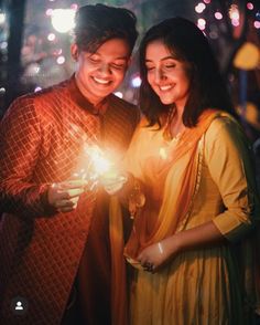 a man and woman standing next to each other holding a lit candle in their hands