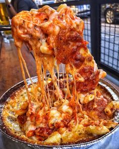 someone is taking a slice of deep dish pizza with cheese and tomato sauce on top