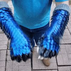 a person with blue and black feathers on their feet standing in front of a brick walkway