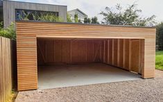 a large wooden garage sitting next to a lush green field