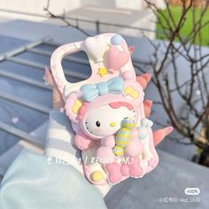 a hello kitty cell phone case on someone's hand with a tree in the background