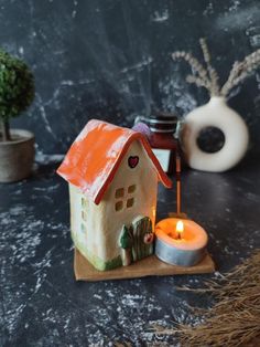 a small house sitting on top of a table next to a potted plant and candle