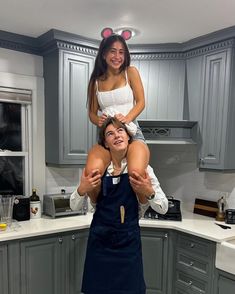 a woman is holding up a man in the kitchen