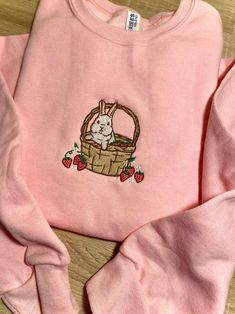 Introducing our Strawberry Basket Bunny Embroidered Sweatshirt 2D Crewneck Sweatshirt, a delightful and charming addition to your wardrobe. Designed for both men and women, this sweatshirt is a perfect blend of comfort, style, and versatility. At first glance, the detailed embroidery of a cute bunny nestled in a basket of fresh strawberries catches your eye. The intricate stitching brings the design to life, adding a touch of playfulness to your outfit. Made with precision and care, this embroid Strawberry Embroidered Sweatshirt, Croquette Outfits, Cute Sweatshirts Outfits, Makeup Embroidery, Crew Neck Embroidery, Sweatshirt Design Ideas, Strawberry Basket, Shirt Outfit Ideas, White Editorial