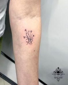 a small tattoo on the leg of a person's left arm, with flowers and leaves