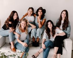 a group of young women sitting on top of a white couch next to each other