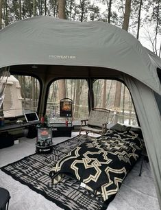 a tent is set up in the woods with chairs and an area rug on the floor