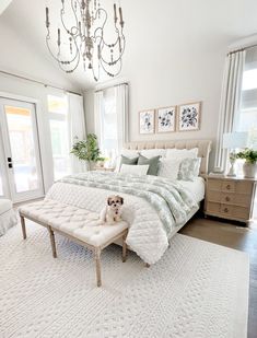 a dog sitting on a bench in front of a bed with white sheets and pillows