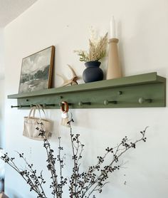 there is a vase with flowers on the shelf next to it and two pictures hanging on the wall